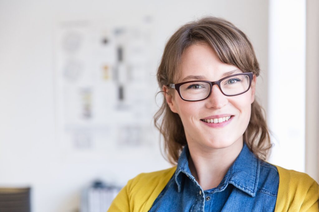 Portrait of young woman wearing eye glasses looking at camera smiling